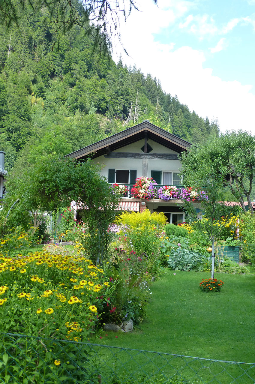 Chalet caché par la végétation et les massifs de fleurs