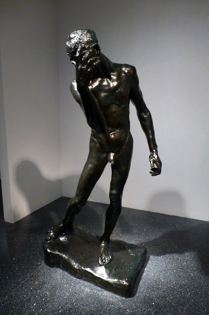 Statue de bronze d'un homme se masquant le visage