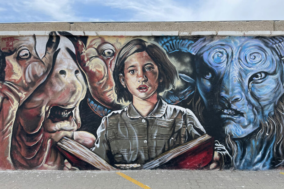 Street art représentant une jeune fille lisant un livre entourée de monstres