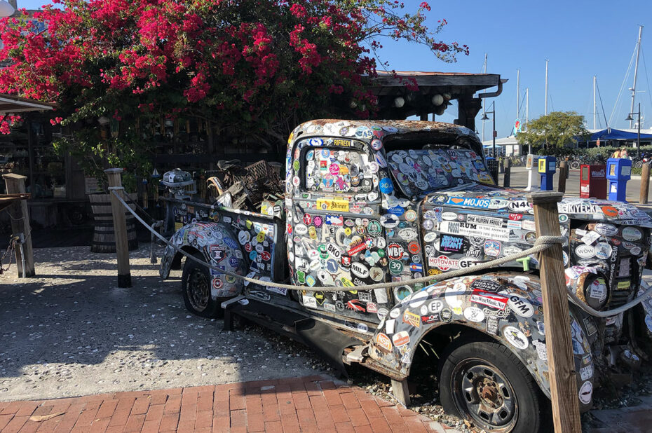 Vieux camion recouvert d'autocollants devant un bougainvillier