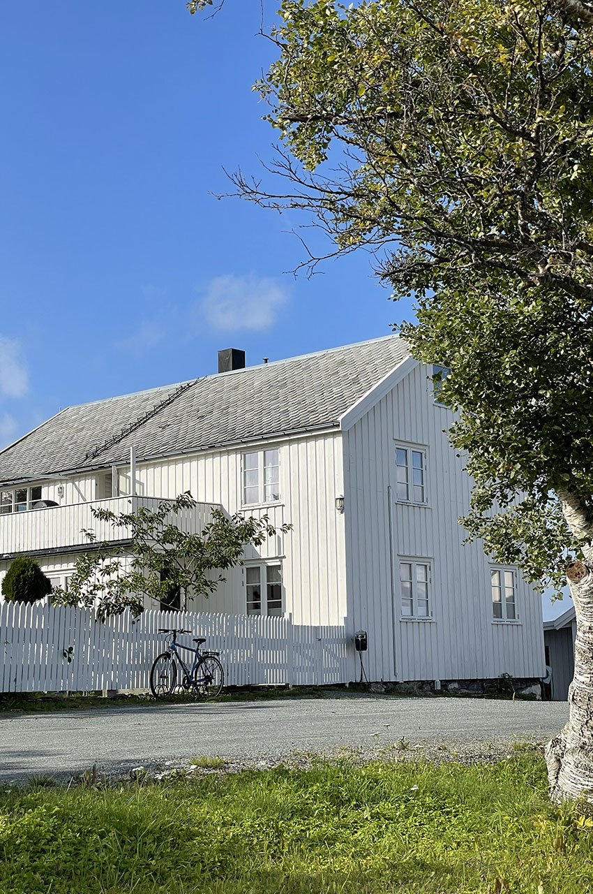 Belle maison blanche en bois avec un vélo devant la clôture