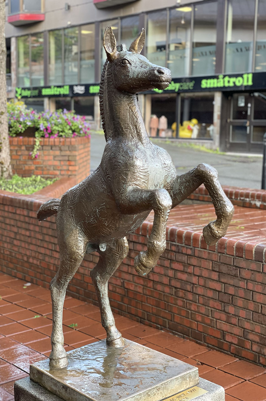 Statue d'un cheval cabré dans une rue commerçante