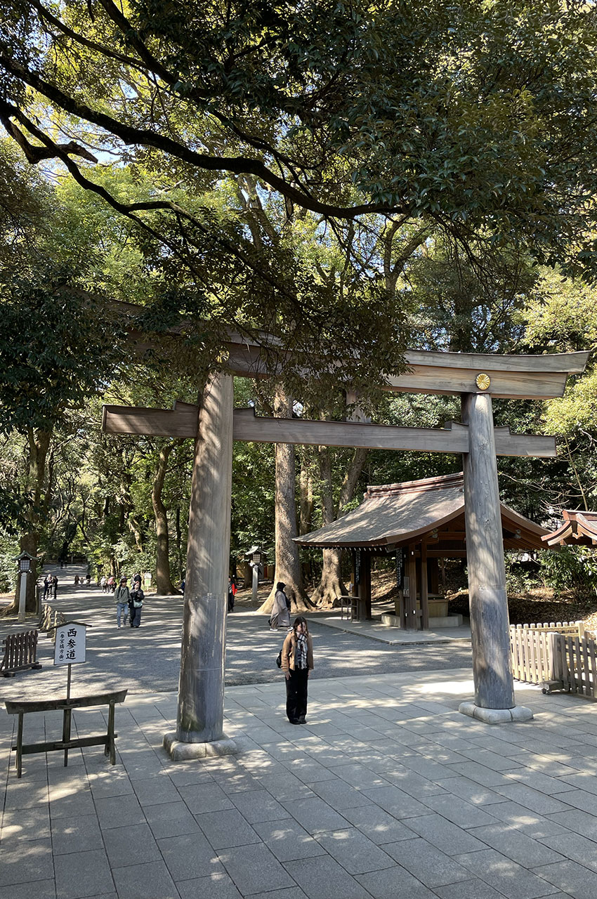 Une Japonaise s'incline sous le torii, seuil sacré de l'entrée du sanctuaire